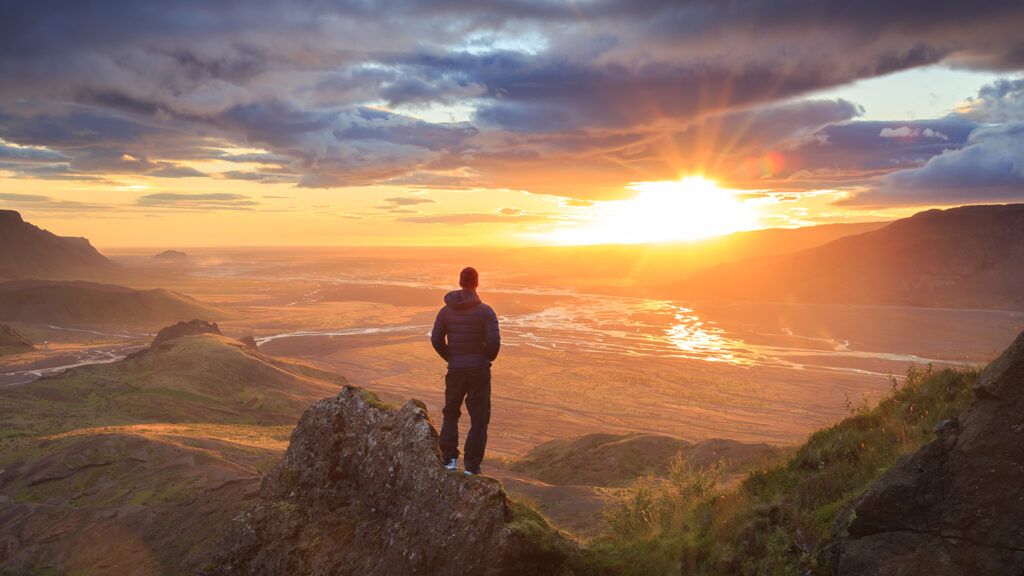 A hiker gazes at a mountain sunrise