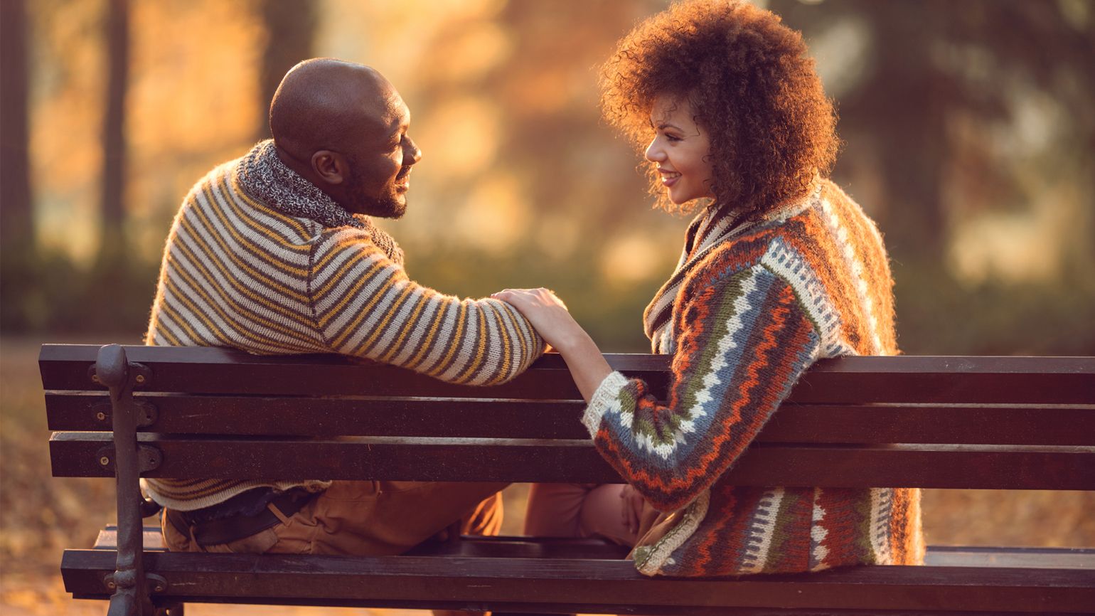 A loving couple gaze at each other while sitting on a park bench