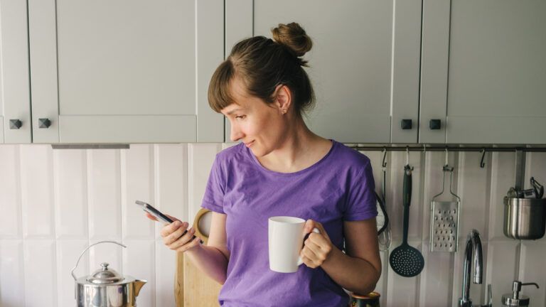 Woman signing up for a lent prayer program email on her phone while in her kitchen