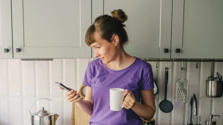 Woman signing up for a lent prayer program email on her phone while in her kitchen