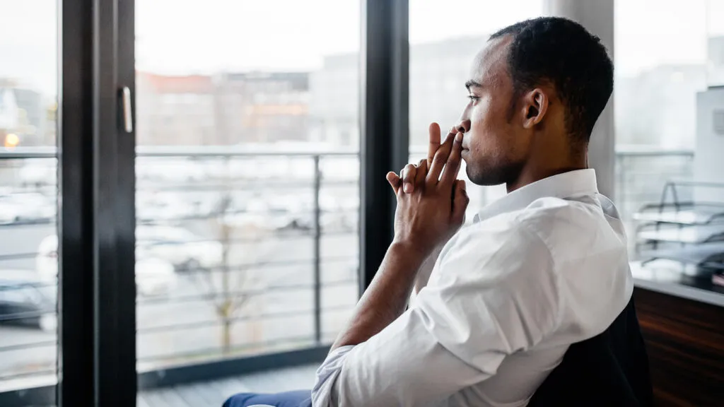 A contemplative man gazes out the window at the city