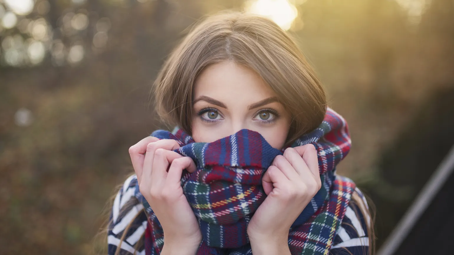 Portrait of a beautiful young woman with face wrapped with a plaid scarf.