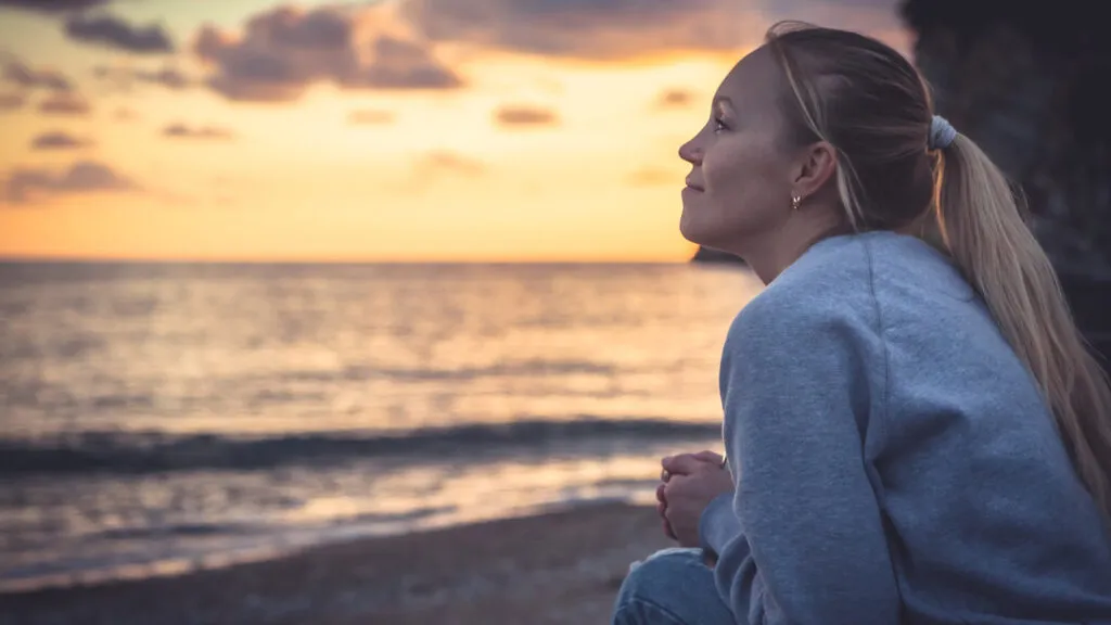 Smiling woman looking with hope into horizon during sunset at beach