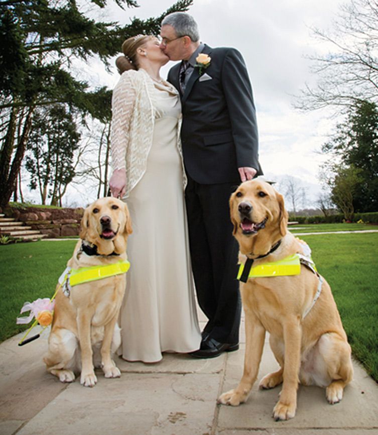 Claire and Mark pose on their wedding day with guide dogs Venice and Rodd