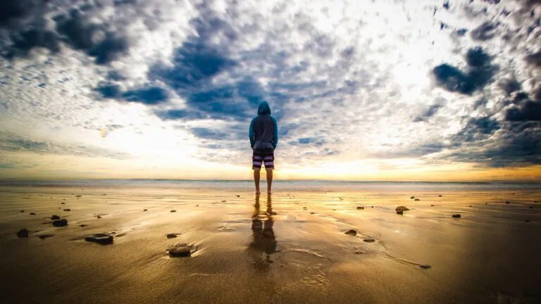 A young person on the beach at sunset