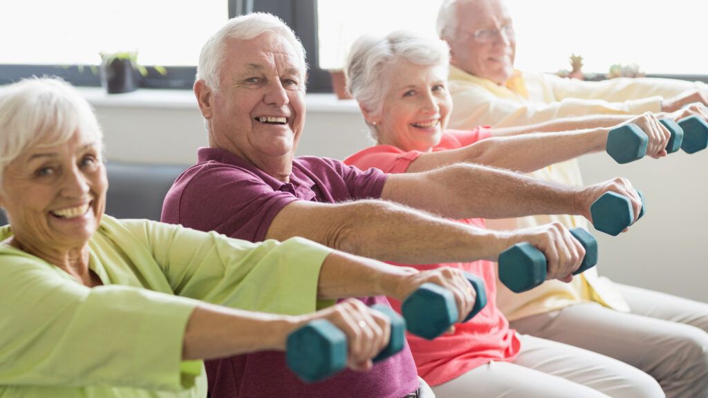 A group of enthusiastic senior citizens doing weight training.