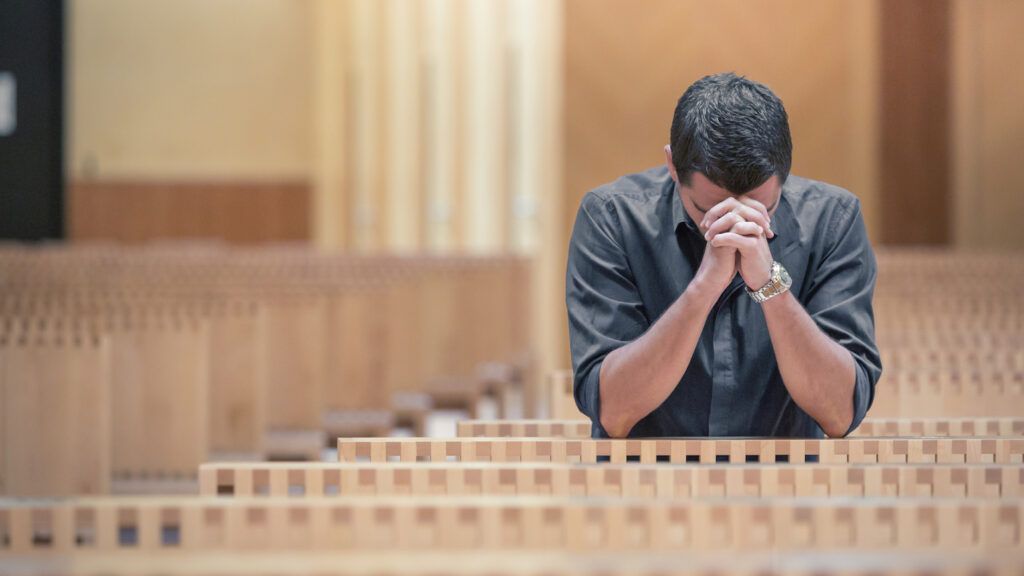 A closeup of a man's hands clasped in prayer