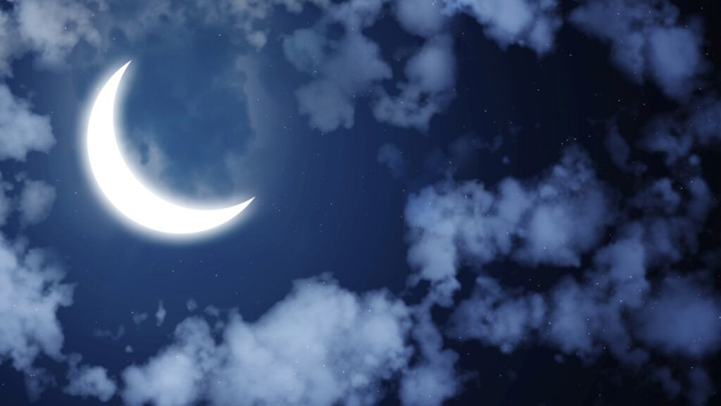 The night sky illuminated by a crescent moon.