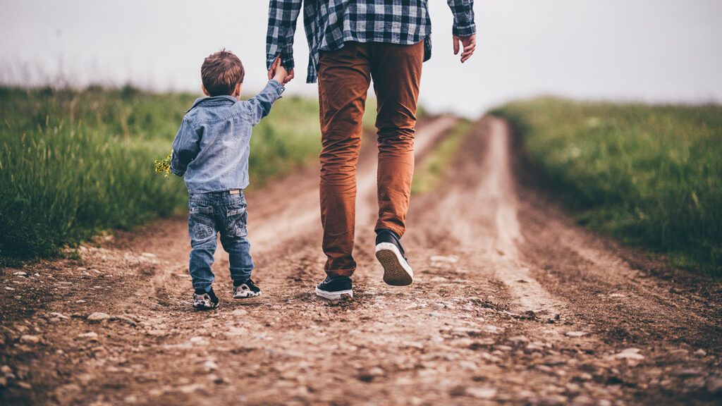 A father and his son stroll down a country lane