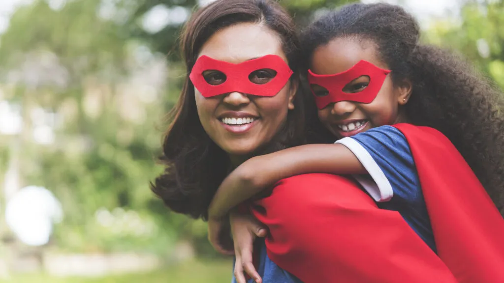 Mother giving piggyback to daughter in costume