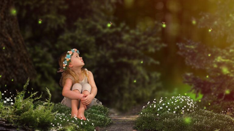 A little girl watches fireflies in a meadow on a warm summer night