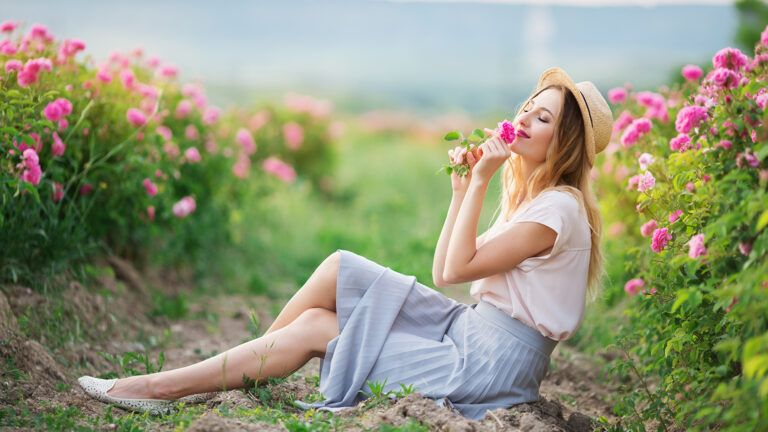 A young woman smells a wild flower on a warn summer evening