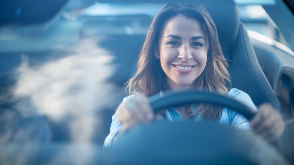 A smiling woman at the wheel of her car