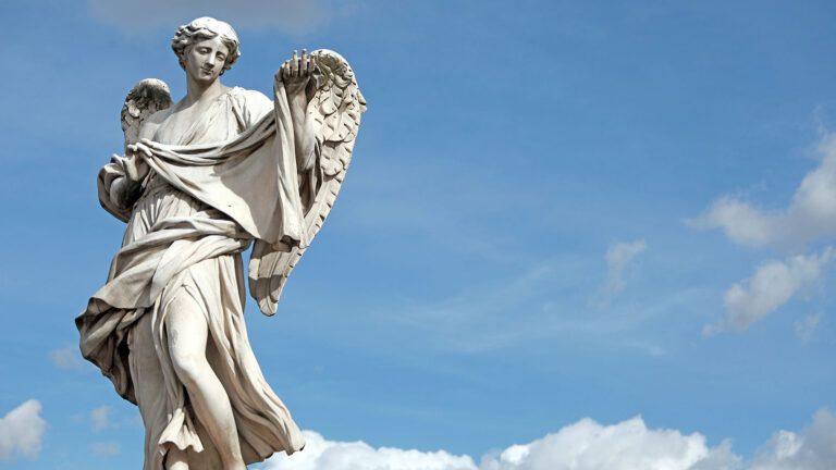 An angel statue stands with blue sky and puffy clouds behind it