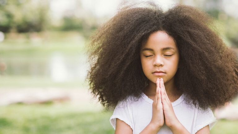 A young girl clasps her hands in prayer