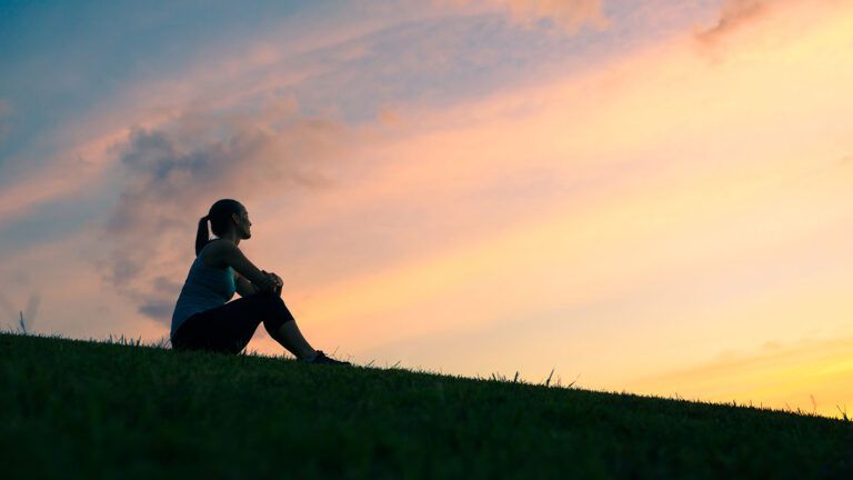 A woman enjoys a moment of peace and calm at sunrise