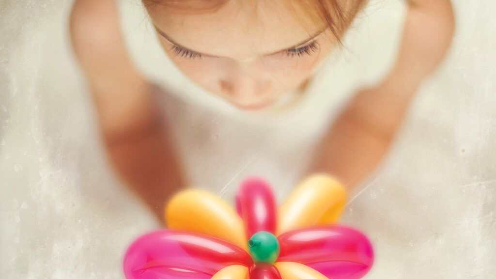 A mysterious little girl holding a balloon flower.