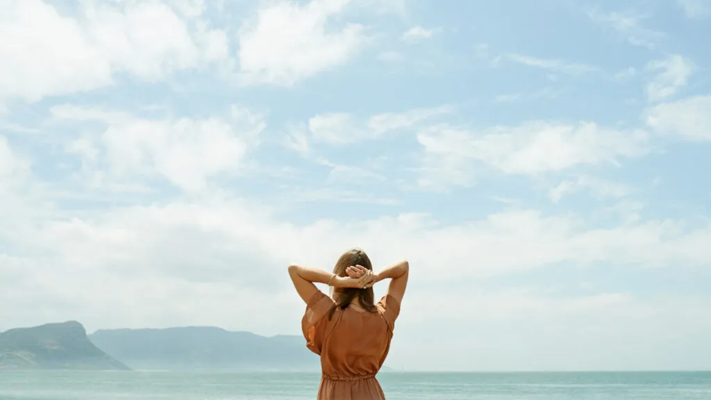 Rearview shot of a woman looking out at the ocean with sky above