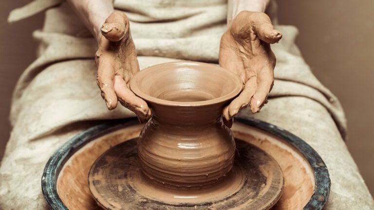 A woman's hands throwing a vase on a pottery wheel