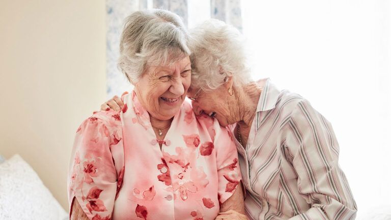 Two senior women forget their differences and laugh together