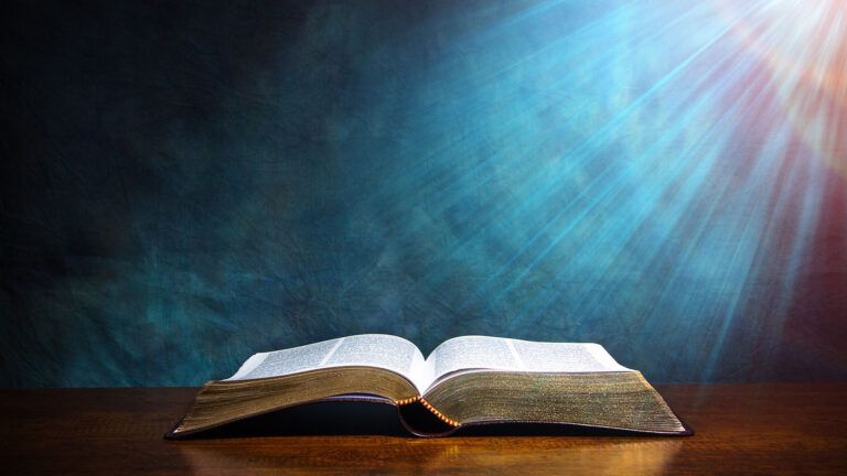 Glowing light shines down from above, illuminating an open Bible