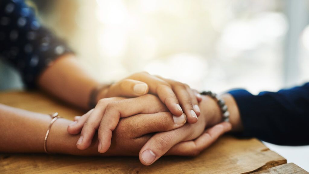 Closeup shot of two unrecognizable people holding hands in comfort.