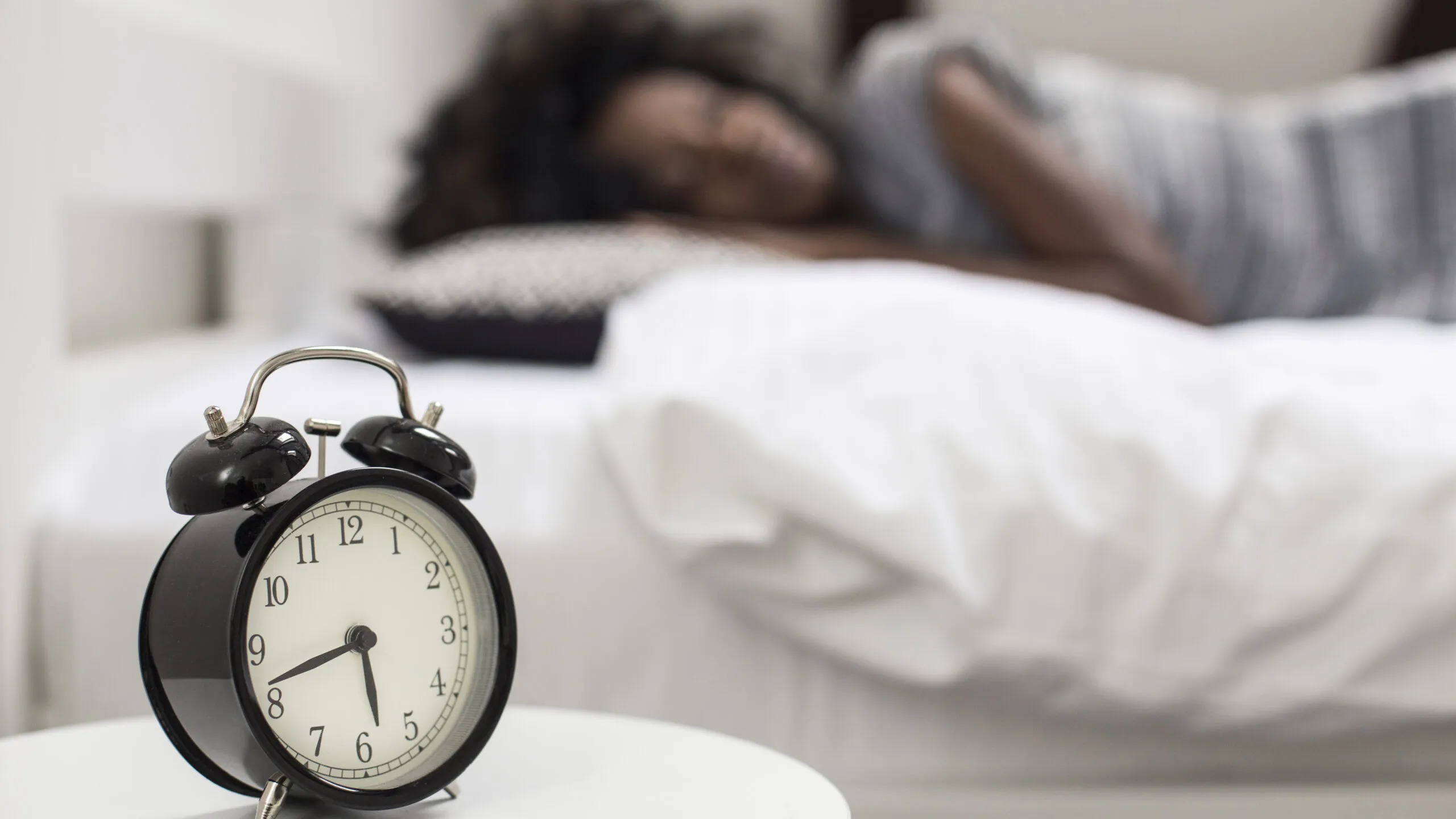 Alarm clock with woman sleeping in the background