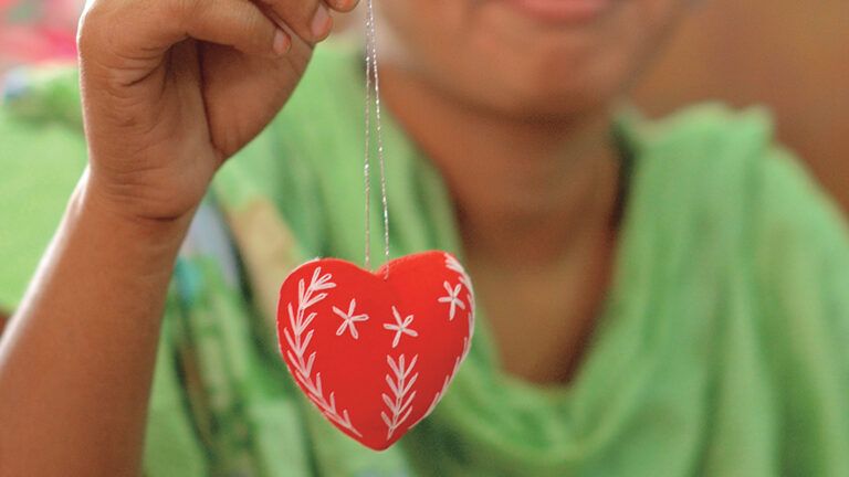 A young woman displays the red heart she has made