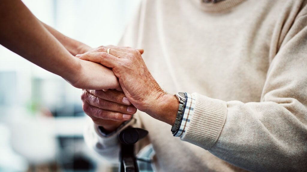 Cropped shot of an female nurse holding her senior patient's hand in comfort.
