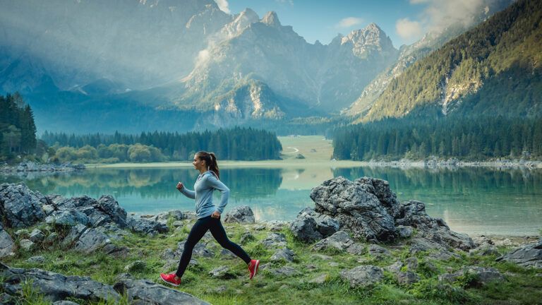 A woman athlete runs by a mountain lake