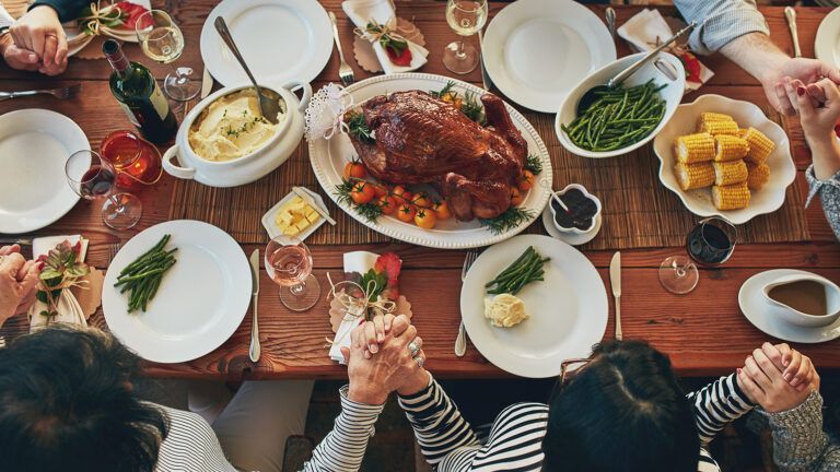 A family holds hands in prayer at the Thanksgiving dinner table
