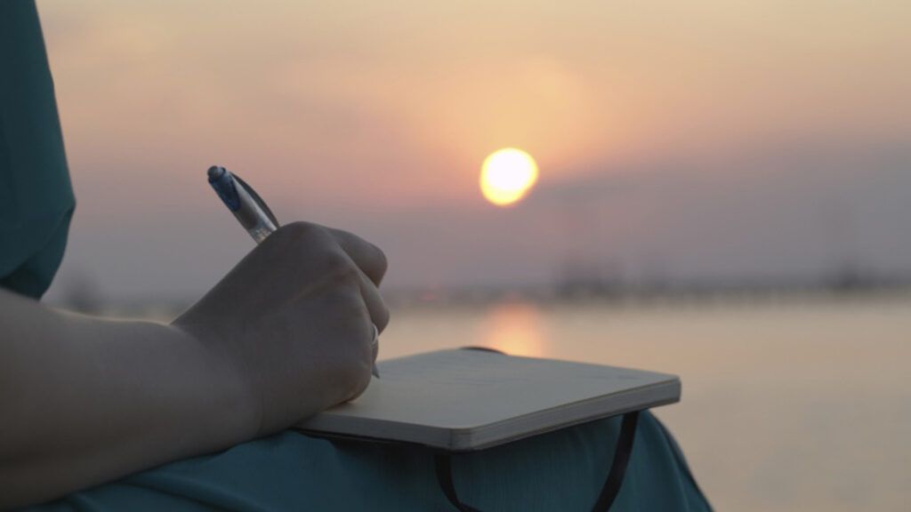 A woman journaling during sunset.