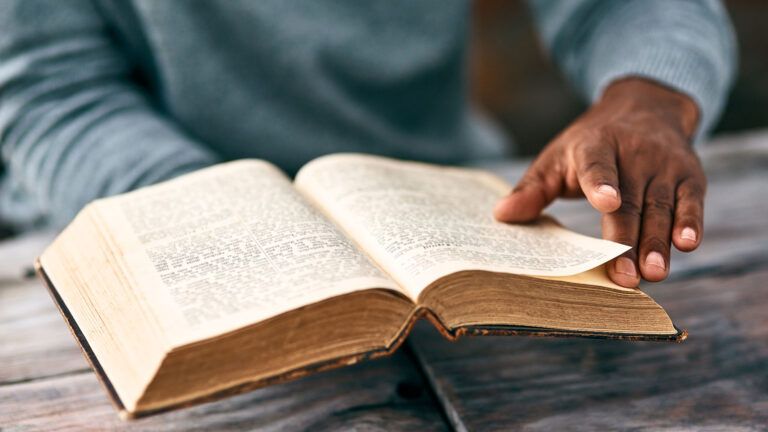 A man's hands clasp an open Bible