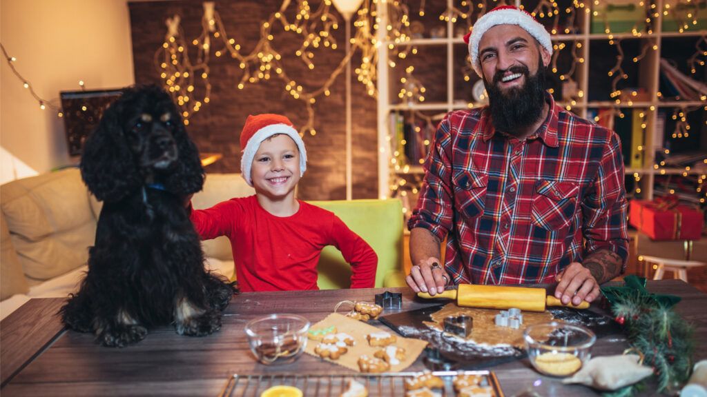 A father and son baking gingerbread cookies with their dog.