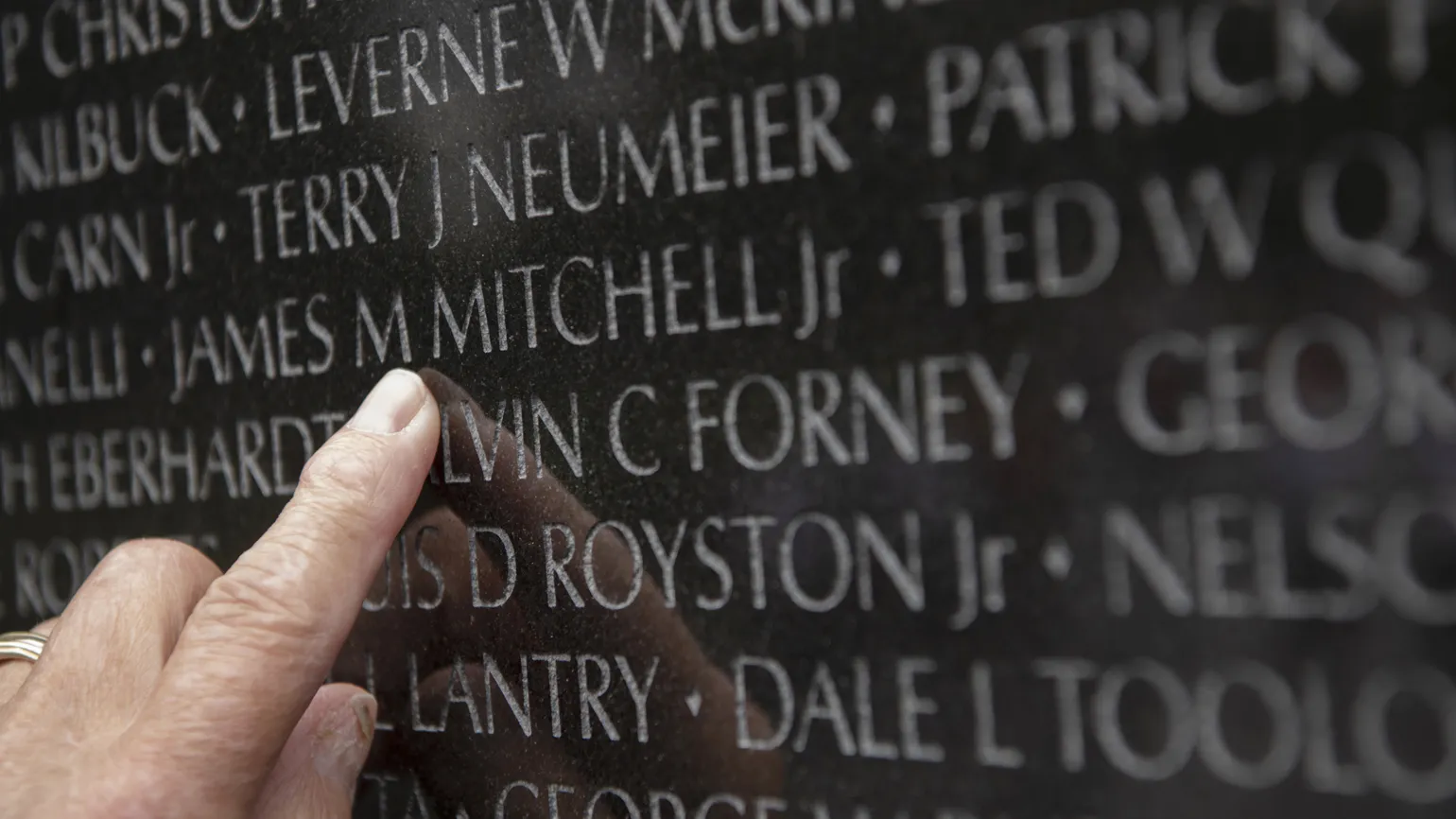 Eddie points to his beloved comrade's name on the wall