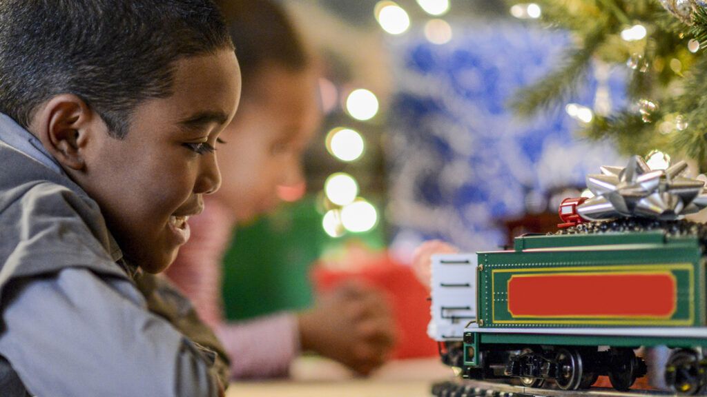A young boy watches a Christmas toy train.