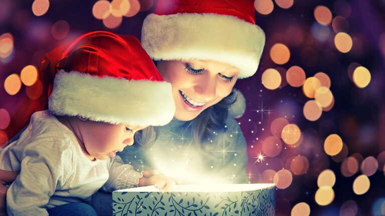 A mother and child in santa hats opening a present