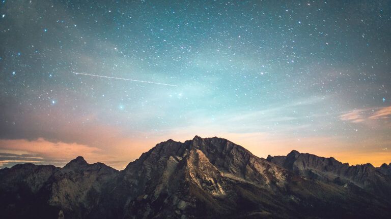 A starlit early-evening sky over a mountain