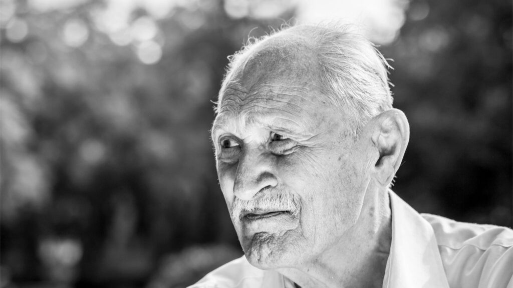 A black and white portrait of a senior veteran in a park.