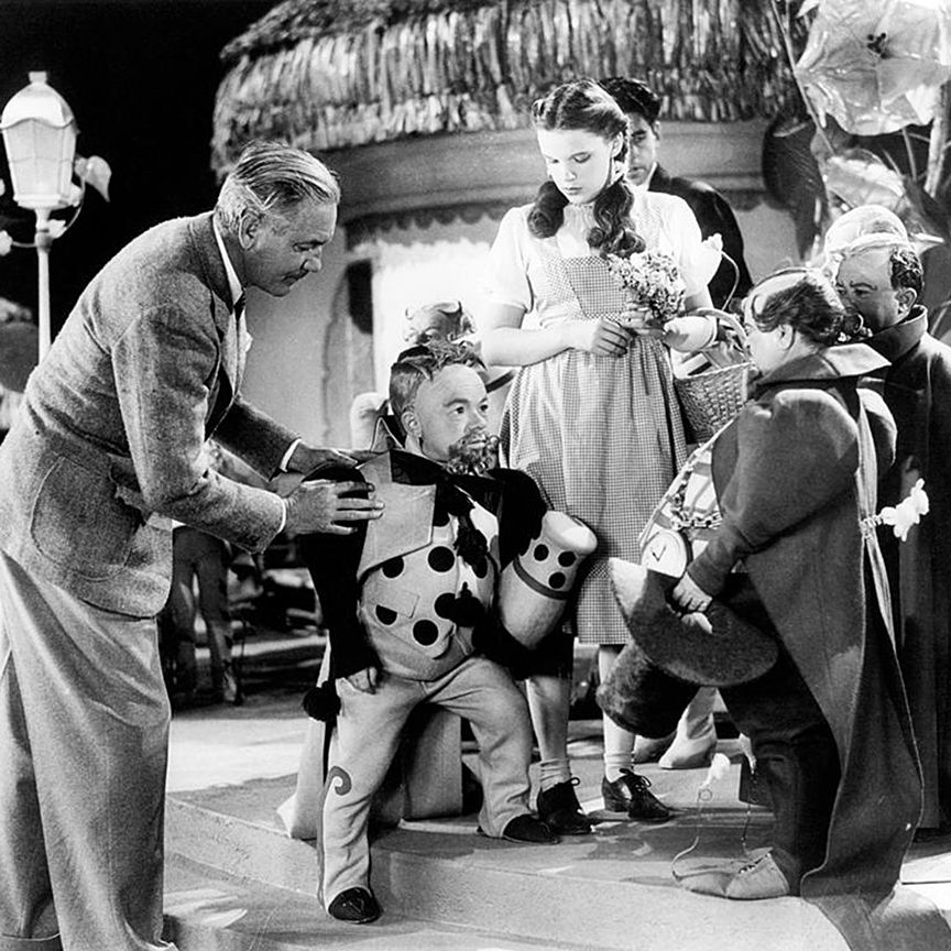 Victor Fleming (left) works with Judy Garland and some of the actors who played the Munchkins