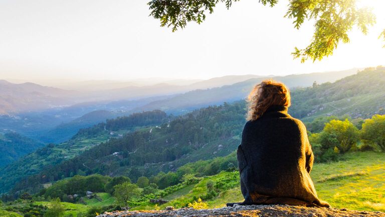 A woman looks out over a scenic vista from a hilltop