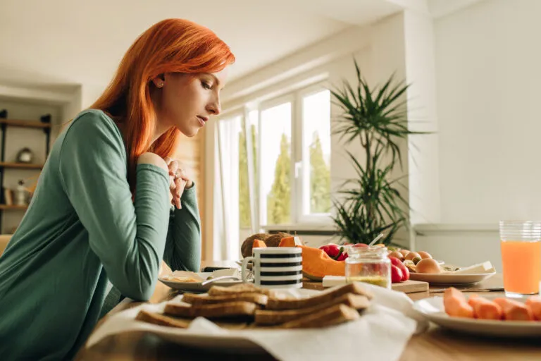 Woman at the table saying a lenten prayer for fasting