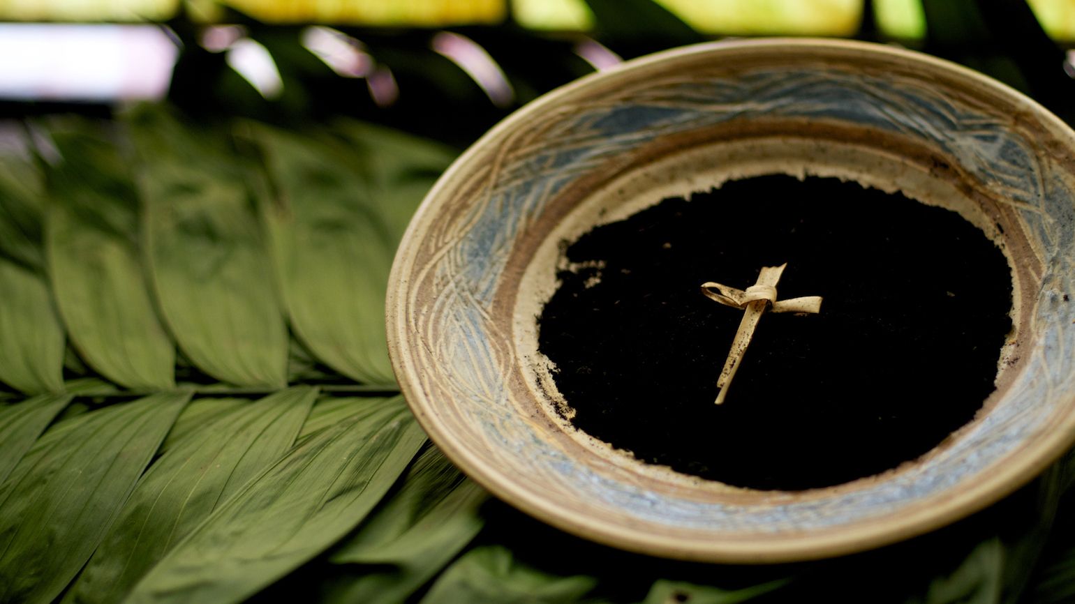 Ashes and a cross in a bowl on top of palm fronds for an ash wednesday reflection service