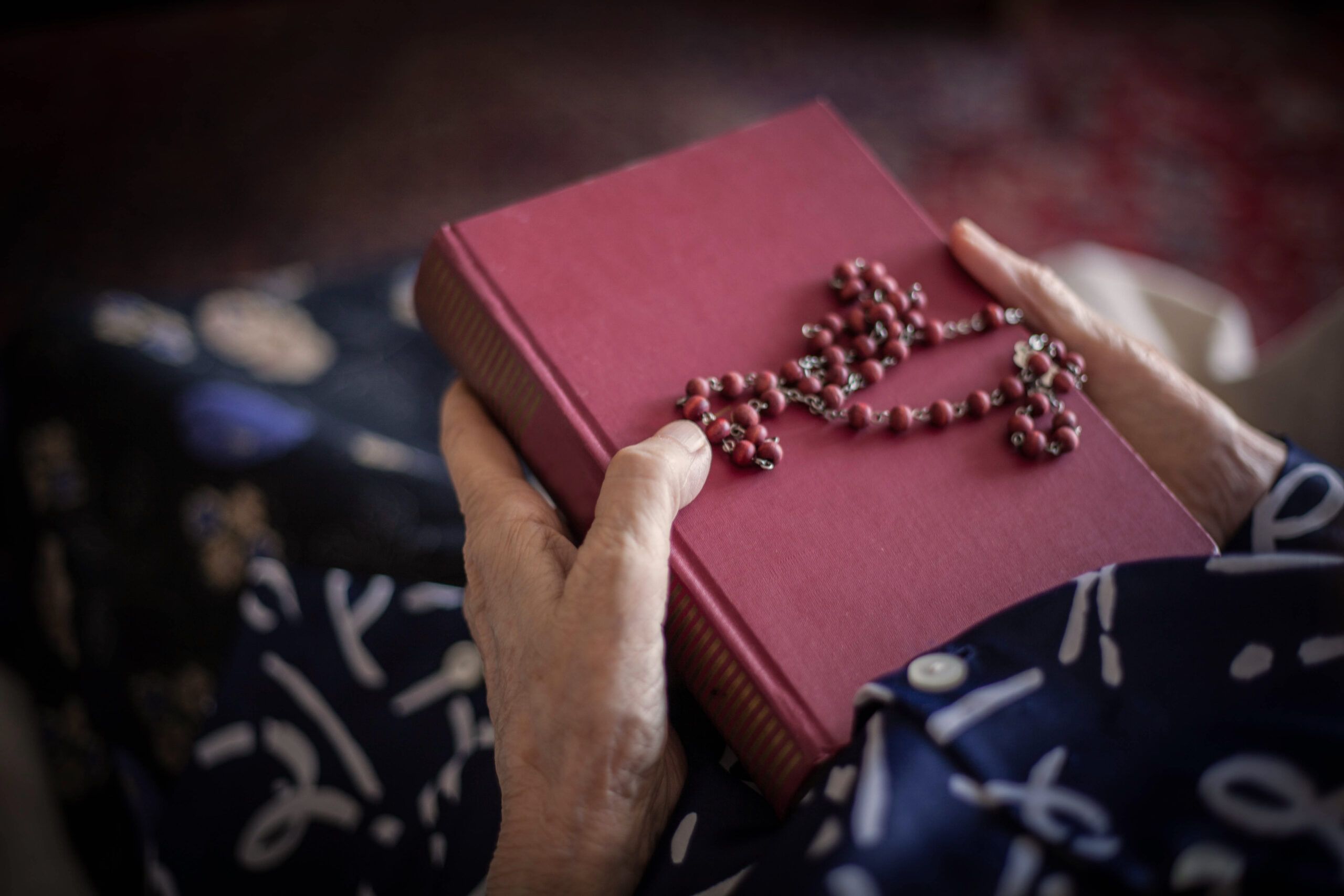 Hands clutching a bible and rosary