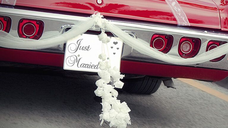 The rear bumper of a red car with a Just Married sign on it