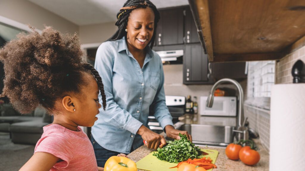 A mother and her young daughter work together to prepare a healthy meal