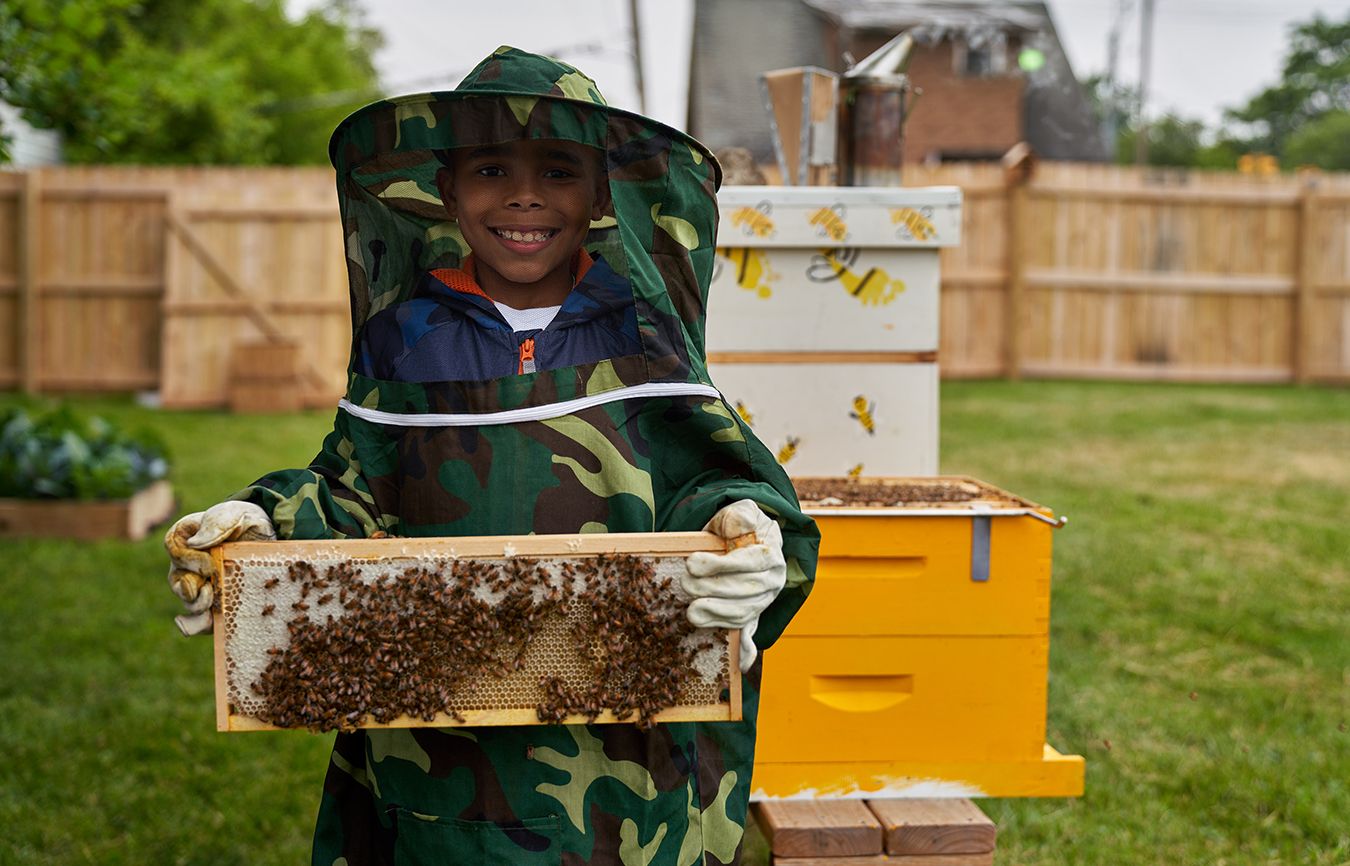 A smiling boy displays a board of bees