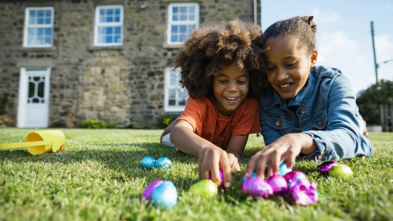 Brother and sister lie in a field looking at easter quote eggs