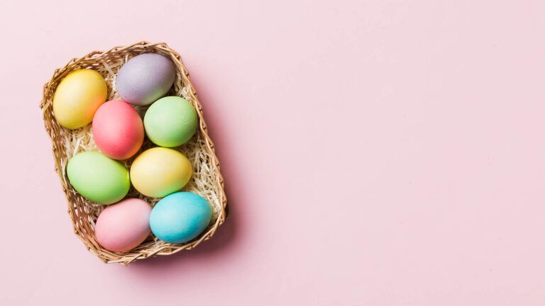 Colorful easter eggs with quotes in a basket on a pink background
