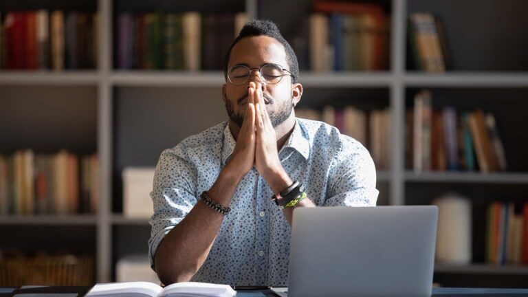 Man saying his spring prayers at his work desk and laptop